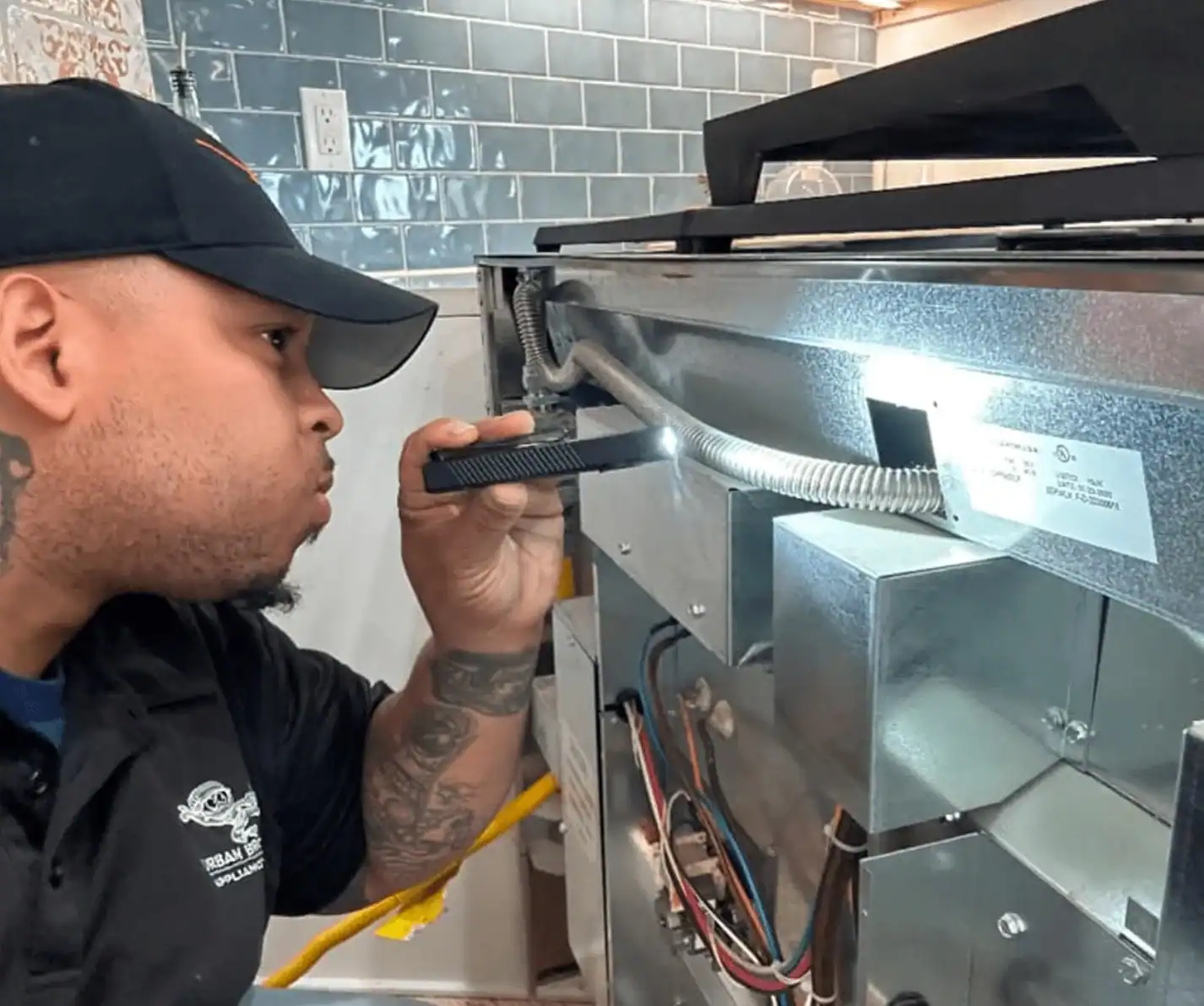 Technician inspecting appliance wiring with flashlight